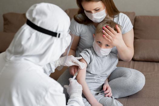 Doctor in personal protective suit or PPE inject vaccine shot to stimulating immunity of a boy at risk of coronavirus infection. Coronavirus,covid-19 and vaccination concept