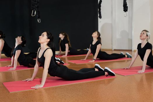 Young athletic girls warm up before training in the gym. Flexibility girls do exercises on the floor of a modern gym.