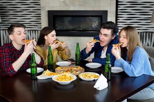 Friends and pizza. Four young cheerful people eating pizza and drinking beer.