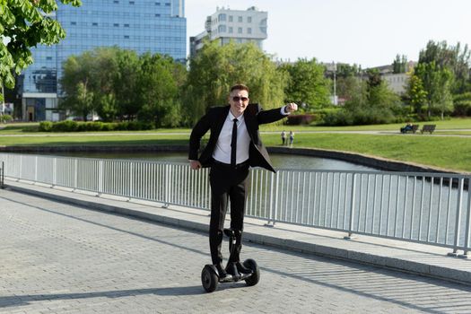 Businessman in a black suit rides a gyro scooter and has fun