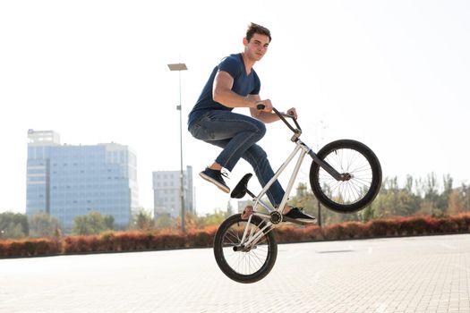 Street portrait of a bmx rider in a jump on the street in the background of the city landscape.
