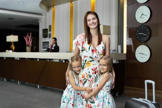 Mother with twin daughters hugging at the hotel reception