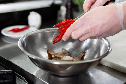 Chef cuts hot chili peppers in the kitchen.
