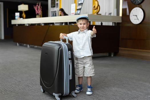Little boy with a big suitcase in the hotel
