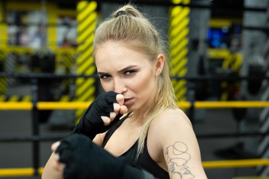 Athletic girl fighter trains in boxing bandages