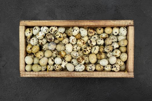 Lots of quail eggs in a wooden box on the background.