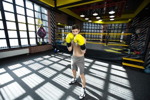 Collected sportsman in the boxing hall practicing boxing punches during training.
