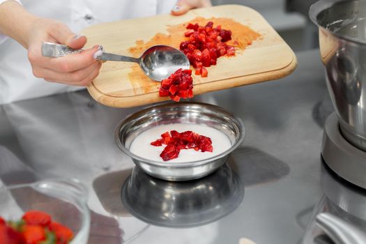 Pastry chef adds sliced strawberries to the cream