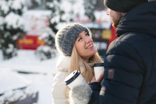 Close-up portrait of a happy couple: men and women hugging and laughing in a winter snow park