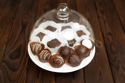 Handmade chocolates on a tray under a glass cover