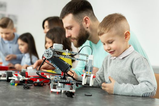 Young father and son assemble a construction kit at a robotics school