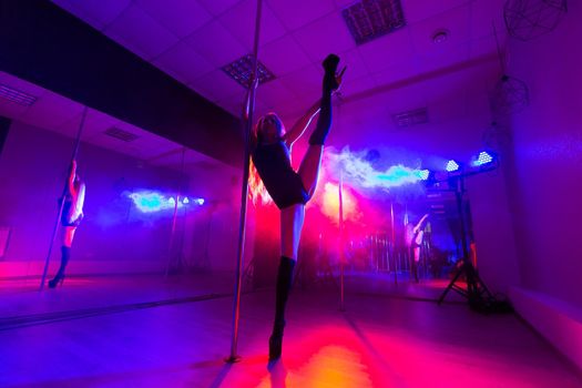 Attractive young sexy female pole dancer performs.