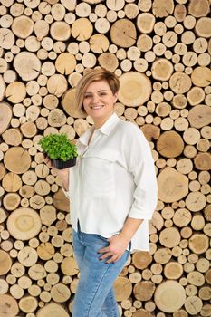 Beautiful young woman holding a micro-green color on the background of a wooden log wall