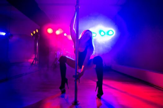 Attractive young sexy female pole dancer performs.