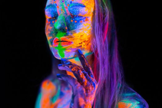 Beautiful young woman in neon light. Portrait of a model with fluorescent makeup posing in UV light with colorful makeup.