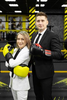 Colleagues, a man and a woman in business suits and boxing gloves in the ring
