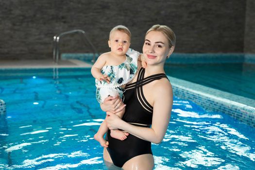 Portrait of a young mother and baby daughter in the pool after a workout