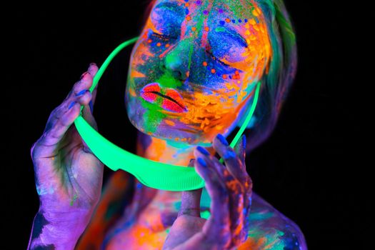 Beautiful model woman wearing glasses with colorful bright fluorescent makeup in neon light, nightclub disco