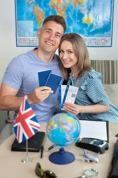 A married couple, a man and a woman, are holding passports with tickets at a travel agency.