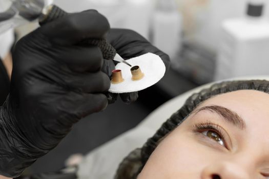 Permanent eyebrow makeup procedure, eyebrow tattooing. The master types paint in the tattoo machine