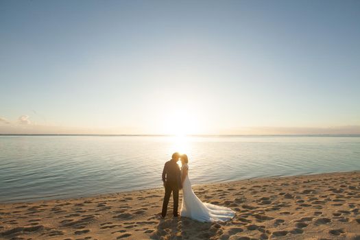 bride and groom meet the sunset on the beach.