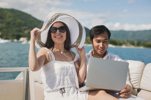 Two business people working with laptop on a sailing boat - sailing trip