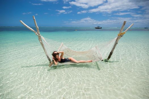 Woman in hammock on tropical beach at island.