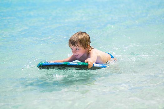 Young surfer, happy young boy in the ocean on surfboard.