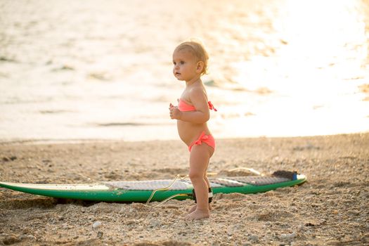A little girl learns to surf on the ocean.