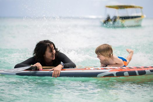 Mom and son have surfing in the ocean on the blackboard.