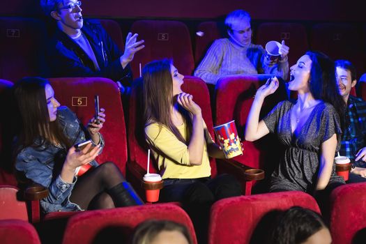 Cheerful group of friends in the cinema is having fun and throwing popcorn