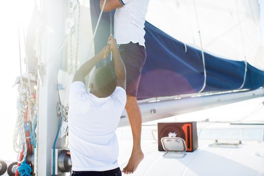 Two sailors discover a sail on a yacht.