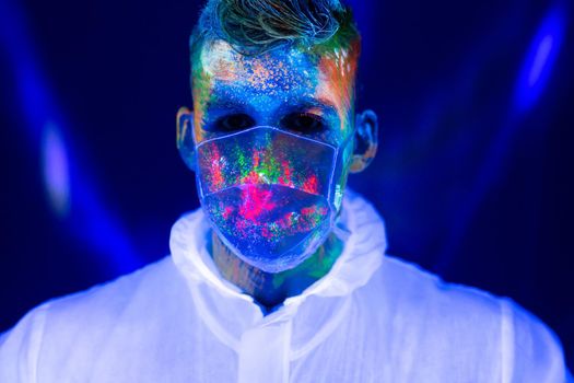 Portrait of man doctor in protective clothes in ultraviolet neon light during coronavirus pandemic. Epidemic, pandemic of coronavirus covid-19.