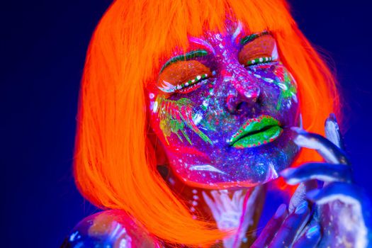 Portrait of woman in with neon makeup. Fluorescent paint in ultraviolet light.