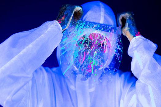 Portrait of woman doctor in protective clothes in ultraviolet neon light during coronavirus pandemic. Epidemic, pandemic of coronavirus covid-19. Doctor, patient in respirator