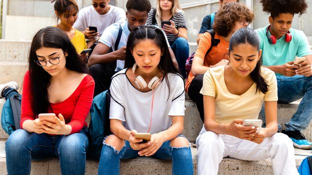 Group of multiracial high school students using mobile phone ignoring each other. Addicted to social media.