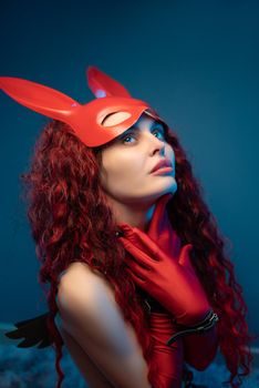 naked girl in a red rabbit mask and long red gloves poses sexually in leather belts and a collar for bdsm games
