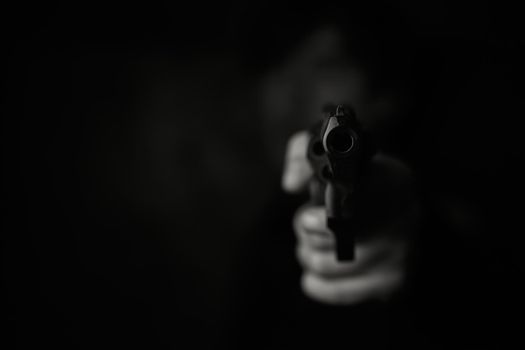Muzzle of gun in man's hand is pointed at camera.