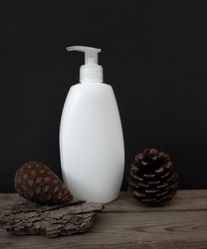 Mockup of a white plastic cosmetic bottle with a dispenser on a black background with tree bark and fir cones