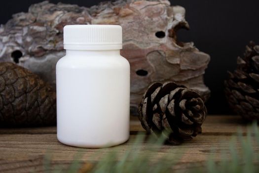 Mockup of a white plastic jar on a black background with tree bark and spruce branches, beauty product packaging.
