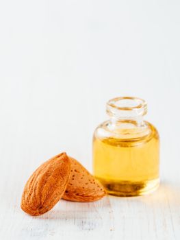 Bottle of almond oil and almonds isolated on white background