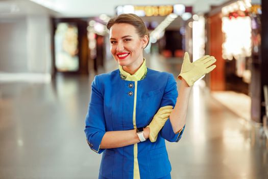 Cheerful woman flight attendant doing hello gesture at airport