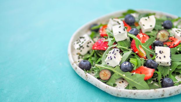 Salad with arugula, feta, strawberry, blueberry