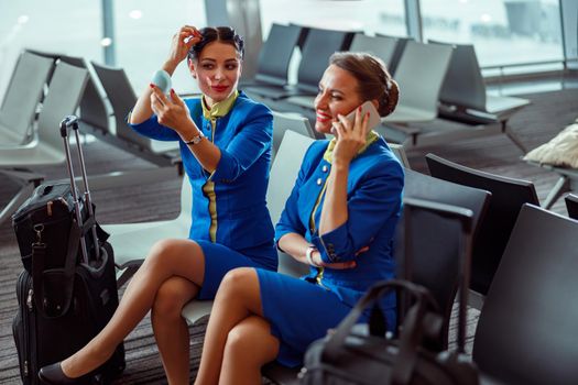 Cheerful women stewardesses waiting for the flight at airport