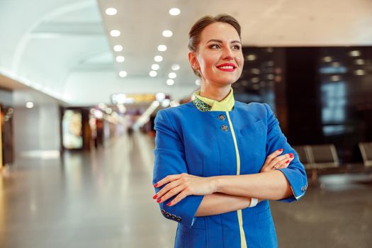 Cheerful female flight attendant standing at airport