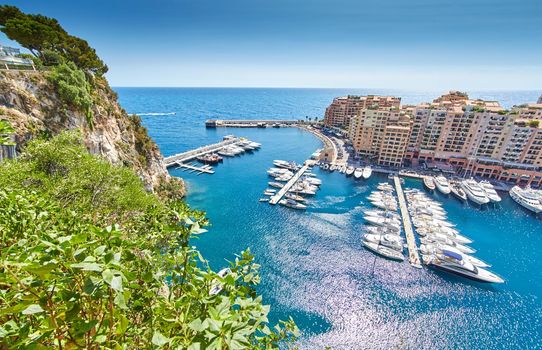 Panoramic image of Port Fontvieille - Monaco, top view from Monaco Ville, azur water, sun reflections on the water, harbour at sunny day, luxury apartments, a lot of yachts and boats, mountain