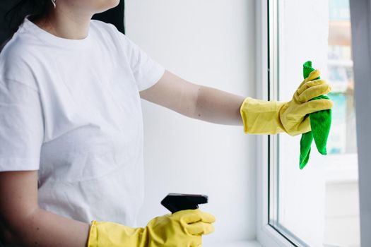 Crop of housewife cleaning dirty window. Concept of housework and apartment service.