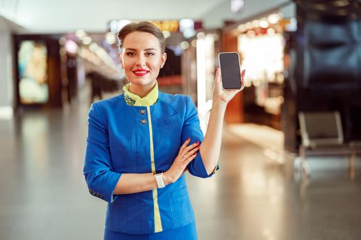 Cheerful stewardesses with cellphone standing in airport terminal