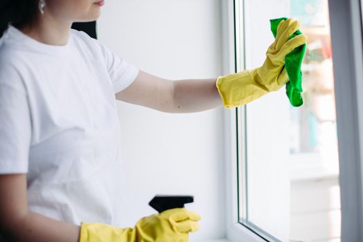 Crop of housewife cleaning dirty window. Concept of housework and apartment service.