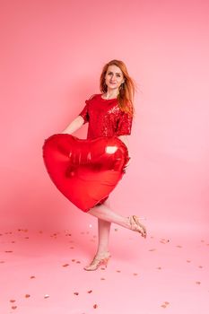 Beautiful redhead girl with red heart baloon posing. Happy Valentine's Day concept